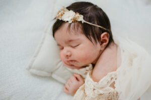 bright airy newborn studio photograph with thick hair and dried flower headband