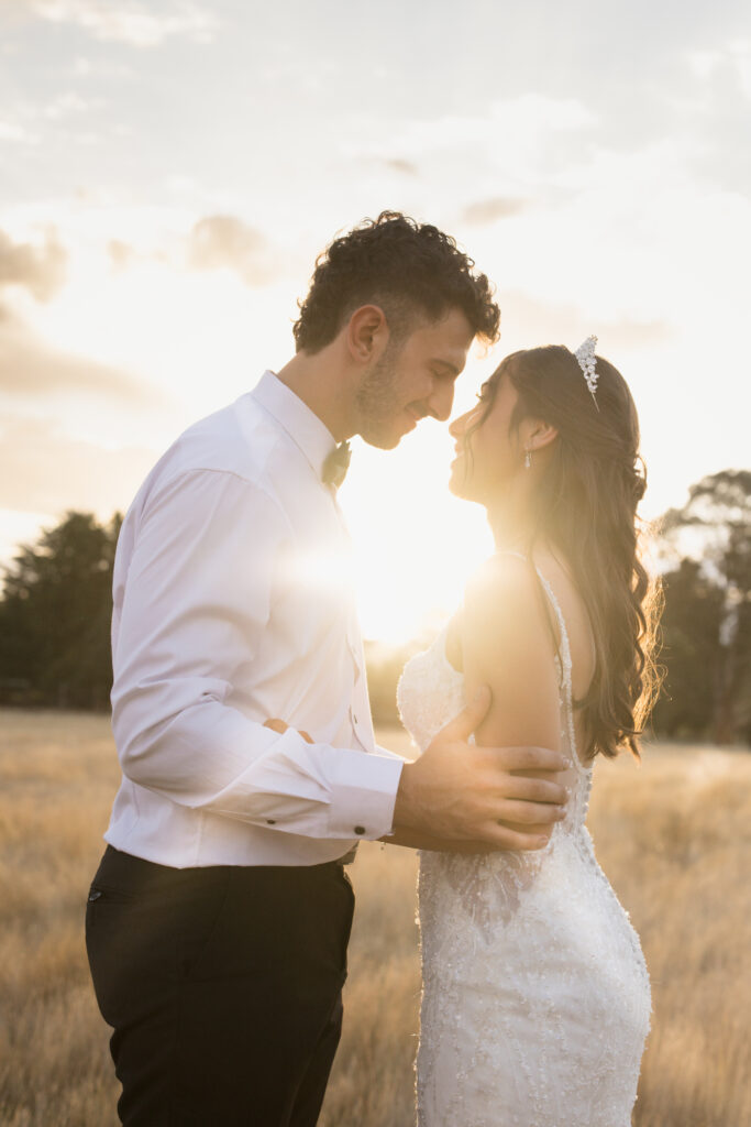 Couple getting Wedding photos at The Hayshed by Meredith Photography during sunset with sunflare