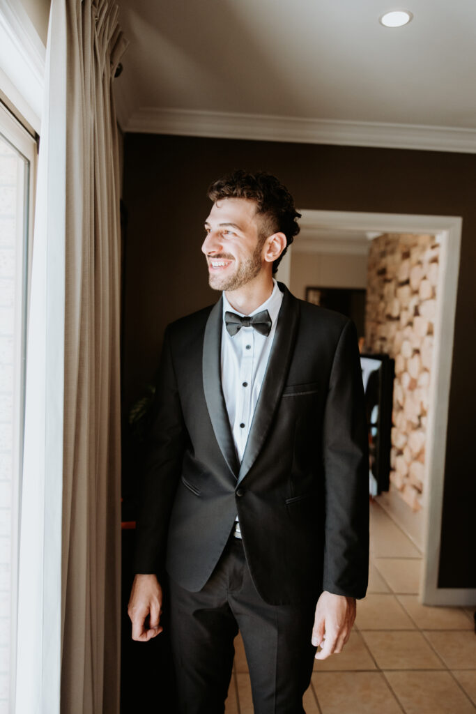 Groom at window shot by Wedding Photographer Meredith Photography